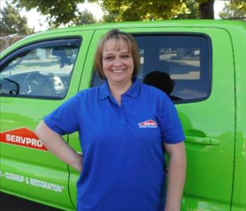 a woman in a blue shirt in front of a green truck